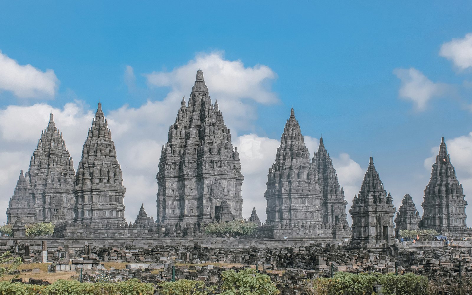 The stone spires of Prambanan temple under a blue sky